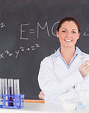 Smilling scientist stanting in front of a blackboard looking at 