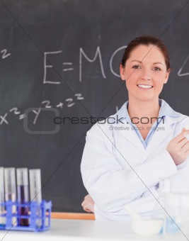 Smilling scientist stanting in front of a blackboard looking at 