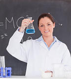 Beautiful scientist showing a container filled up with a blue li