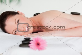 Happy young woman with massage stones and a pink gerbera