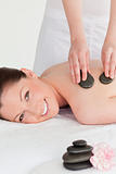 Smiling young redhead woman having a hot stone massage