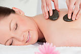 Young woman closing her eyes while having a hot stone massage