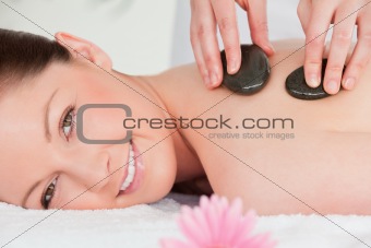 Young woman looking at the camera while having a hot stone massa