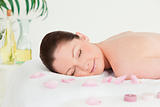 Beautiful woman lying on a massage table with petals and unlight