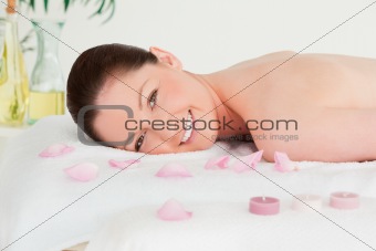 Smiling young woman lying on her belly with petals and unlighted
