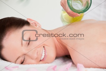 Masseuse putting massage oil on a pretty woman's back