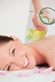 Portrait on a smiling woman having massage oil versed on her bac