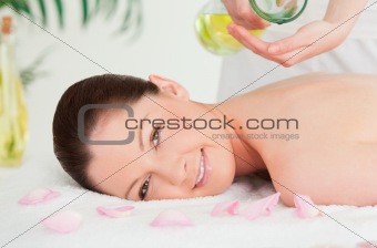 Beautiful woman getting massage oil on her back in a spa