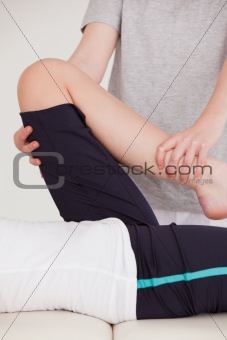 Portrait of a masseuse stretching the leg of a youn woman