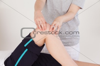 Close up of a masseuse massing the knee of an athletic woman