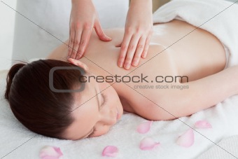 Cute redhead woman having a back massage surrounded by petals