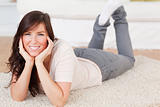 Charming brunette female posing while lying on a carpet