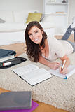 Young good looking woman writing on a notebook while lying on a 