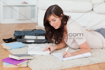Young brunette female writing on a notebook while lying on a car
