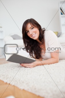 4Young attractive woman reading a book while lying on a carpet