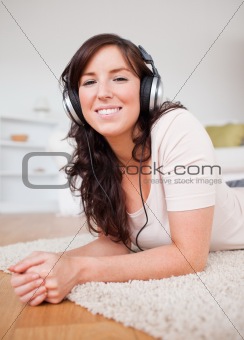 Beautiful brunette female using headphones while lying on a carp