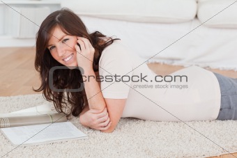 Young beautiful woman reading a magazine while lying on a carpet