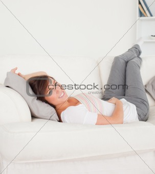Pretty brunette woman posing while lying on a sofa
