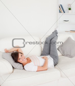 Gorgeous brunette female posing while lying on a sofa