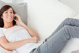Charming brunette female on the phone while lying on a sofa