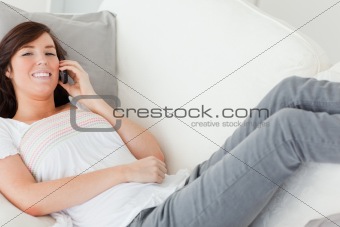 Charming brunette female on the phone while lying on a sofa