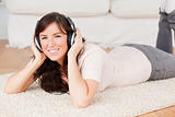 Attractive brunette woman using headphones while lying on a carp