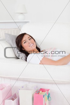 Young beautiful female posing with her shopping bags while lying