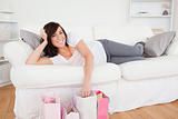Young gorgeous female posing with her shopping bags while lying 