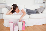 Young cute woman posing with her shopping bags while lying on a 