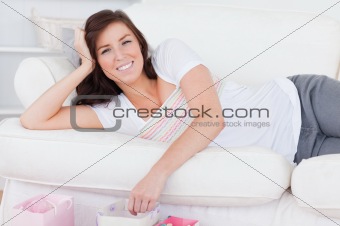 Young charming woman posing with her shopping bags while lying o