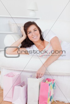 Young lovely woman posing with her shopping bags while lying on 