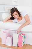 Young gorgeous woman posing with her shopping bags while lying o
