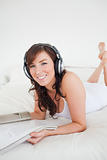 Beautiful female with headphones reading a magazine while lying