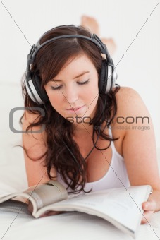 Attractive female with headphones reading a magazine while lying