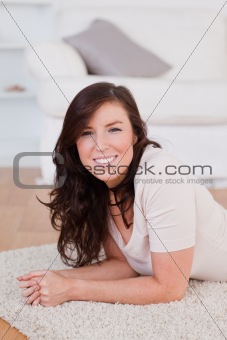Good looking brunette woman posing while lying on a carpet