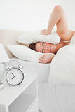 Good looking brunette woman awaking with a clock while lying