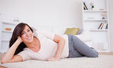 Gorgeous brunette woman posing while lying on a carpet