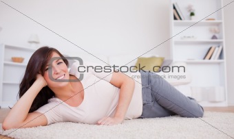 Gorgeous brunette woman posing while lying on a carpet