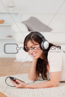 Pretty brunette female listening to music with her mp3 player wh