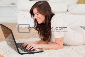 Attractive brunette woman relaxing with her laptop while lying o