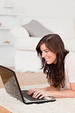 Good looking brunette woman relaxing with her laptop while lying