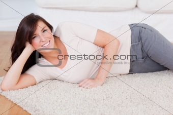 Beautiful smiling woman posing while lying on a carpet