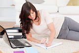 Young attractive woman relaxing with her laptop while writing on