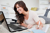 Young charming woman relaxing with her laptop while writing on a