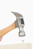 Close up of a hammer driving a nail into a wooden board