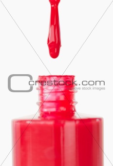 Red nail polish droping in its flask