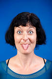middle-aged woman sticking out her tongue - isolated on blue