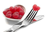Red heart shaped jelly sweets with knife and fork on white