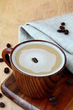 coffee cappuccino in a stylish wooden cup with coffee beans around