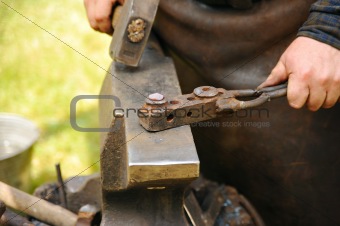 Blacksmith hammering hot steel on anvil